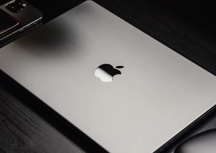 Apple event stage graphic announcing March 4 keynote with MacBook silhouette and Apple logo illuminated in a modern presentation setting.